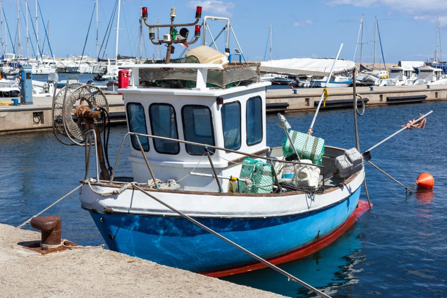 Fishing boat moored at La Caletta Port in Sardinia, Italy, with fishing gear on deck.