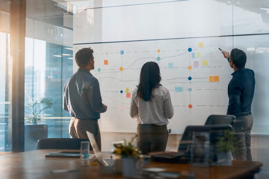 Business team mapping abstract strategy roadmap on large office whiteboard