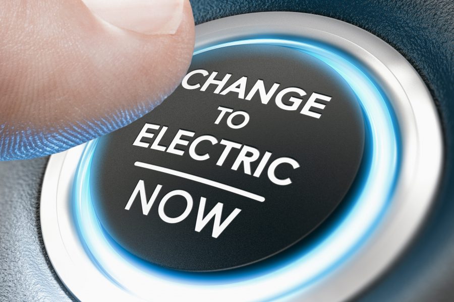 Finger pressing a start button with the message change to electric now. Composite image between a hand photography and a 3D background.