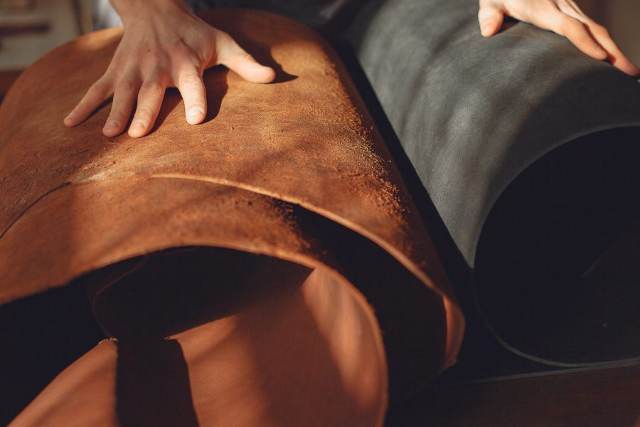 Man working with leather. Professional makes a belts. Man holds a factory in his hands