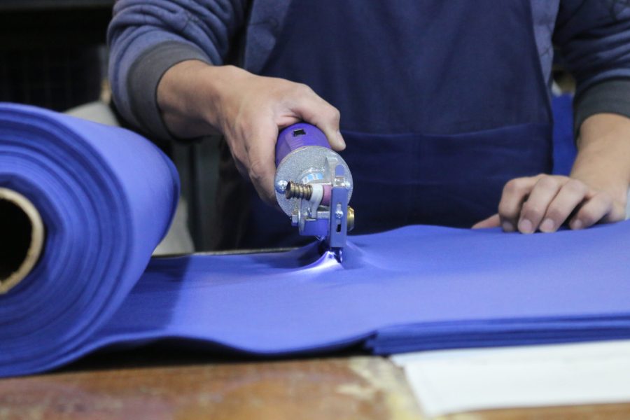 Trabajador de empresa textil cortando tela.
