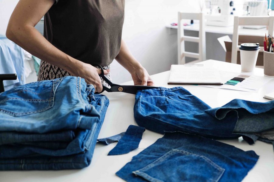 Denim Upcycling Ideas, Using Old Jeans, Repurposing Jeans, Reusing Old Jeans, Upcycle Stuff. Woman seamstress cut and repair old blue jeans in sewing studio