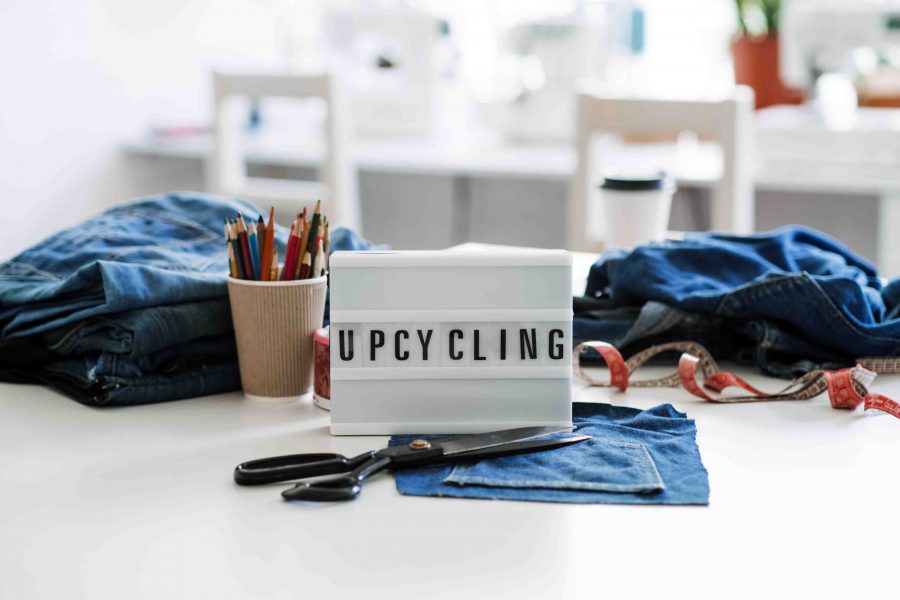 Denim Upcycling Ideas, Using Old Jeans, Repurposing Jeans, Reusing Old Jeans, Upcycle Stuff. Lightbox with text Upcycling, Stack of old blue jeans, scissors, thread and sewing tools in sewing studio