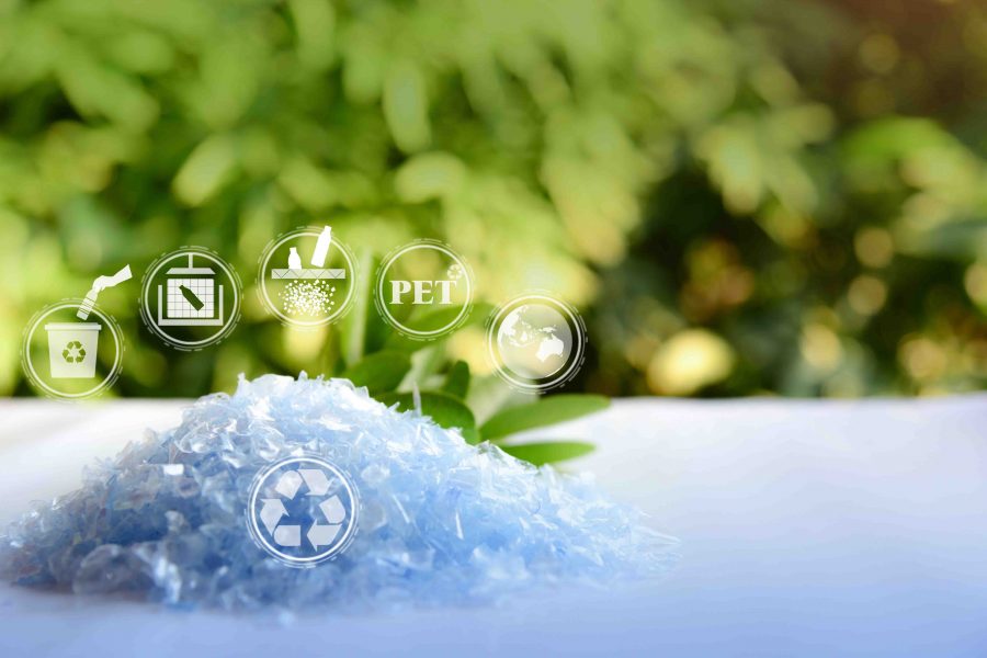 A Pile of PET bottle flakes with green tree blur background.Recy