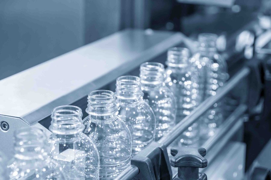 The empty PET bottles  on the conveyor belt for filling process in the drinking water factory. The hi-technology of plastic bottle manufacturing process.