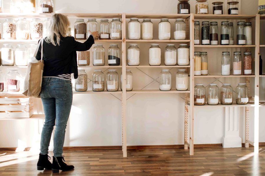 A rear view of attractive young happy woman buying groceries in zero waste shop. Copy space.